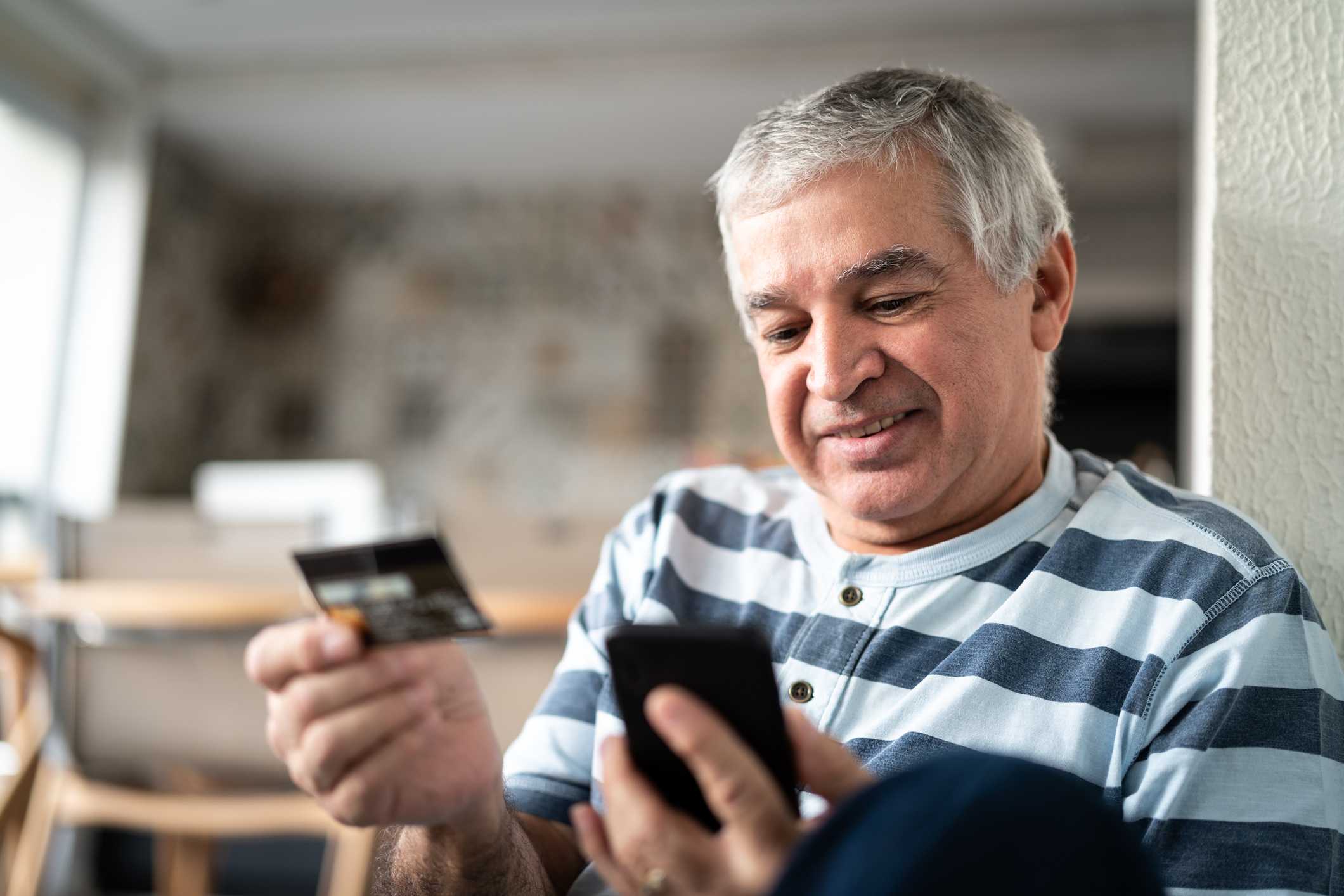Senhor fazendo compras pelo celular com cartão de crédito