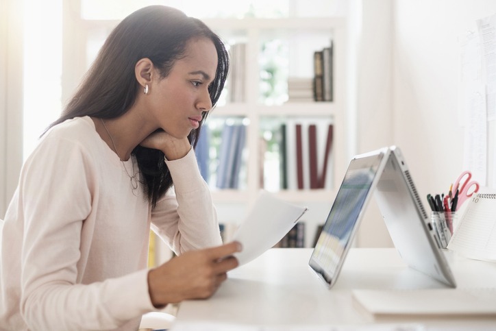 Mulher negra olha para a tela enquanto administra as finanças do próprio negócio