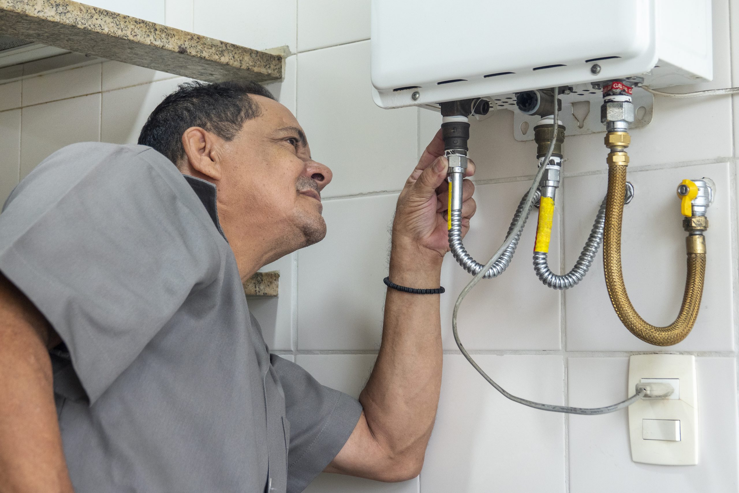 Trabalhador-vestido-de-cinza-analisando-as-conexoes-de-um-aquecedor-a ...