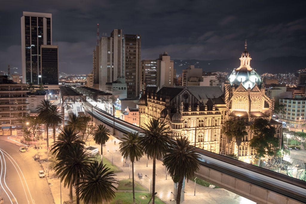 Cena noturna da cidade de Medellín com o metrô chegando na estação